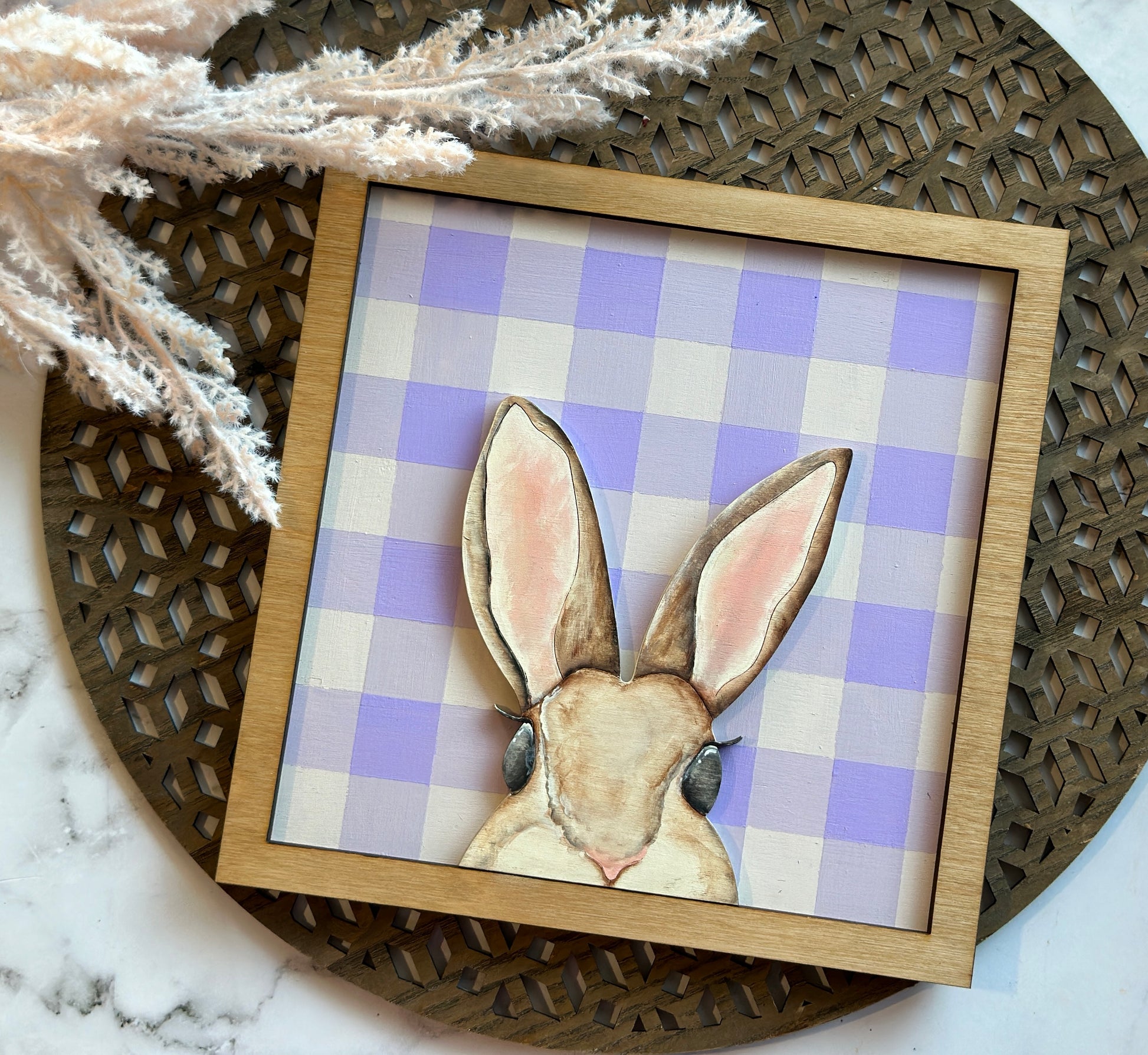 A peekaboo hand painted mouse brown bunny sign over a purple plaid backer with a stained frame.