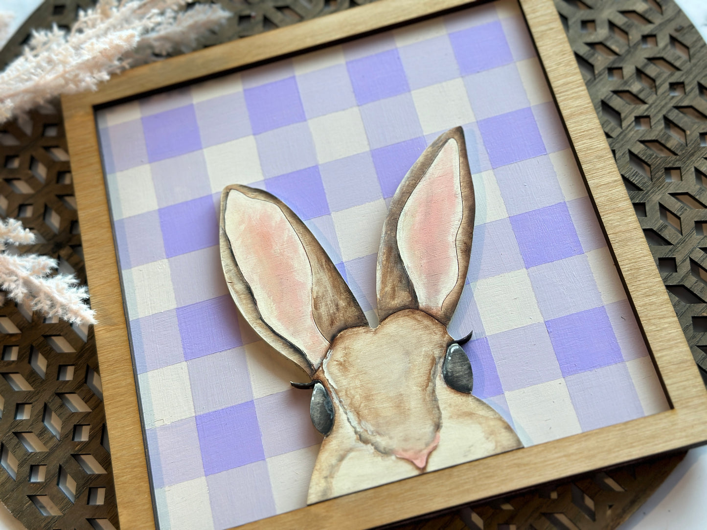 A peekaboo hand painted mouse brown bunny sign over a purple plaid backer with a stained frame.
