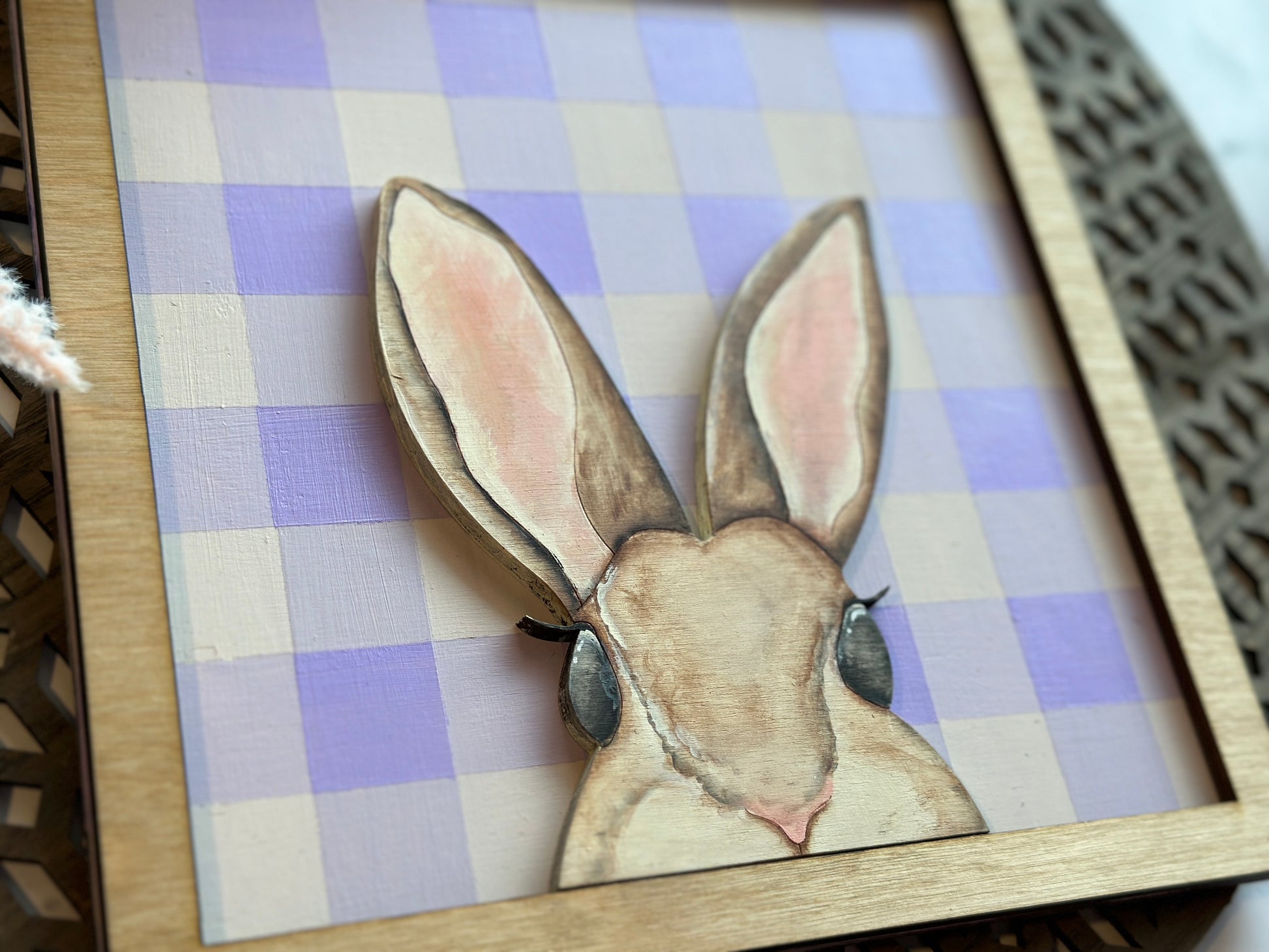 A peekaboo hand painted mouse brown bunny sign over a purple plaid backer with a stained frame.