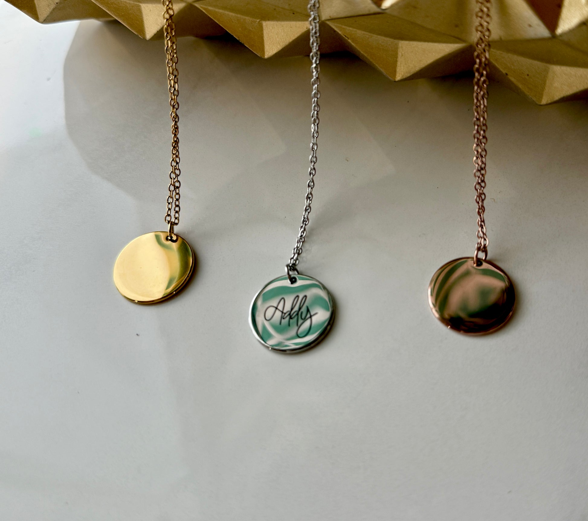 Three necklaces with round pendants on a light gray background