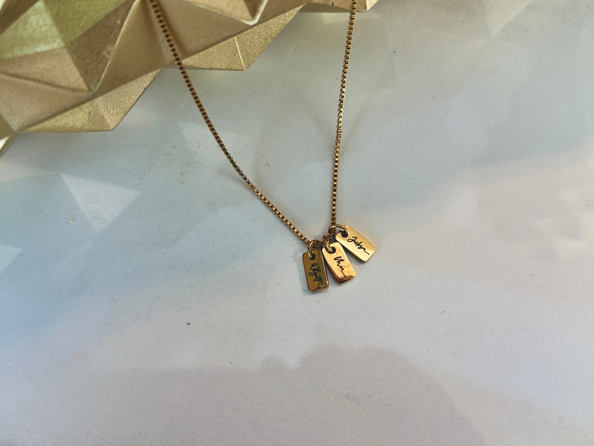 Gold necklace with two tags on a light background