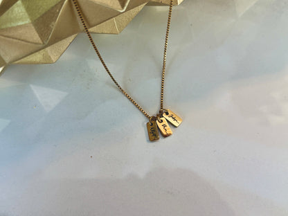 Gold necklace with two tags on a light background