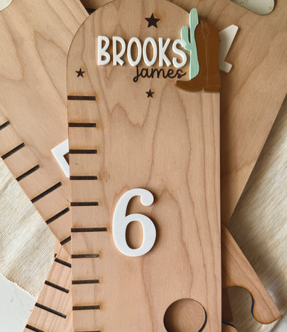 Wooden cowboy themed puzzle growth chart with 'Brooks James' engraving and number '6'