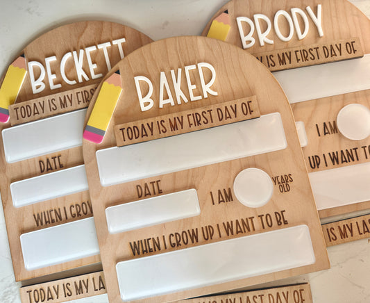 Wooden back to school boards with whiteboard for children's first and last days of school on a marble background.