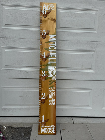 Wooden height chart with moose design against a white garage door background