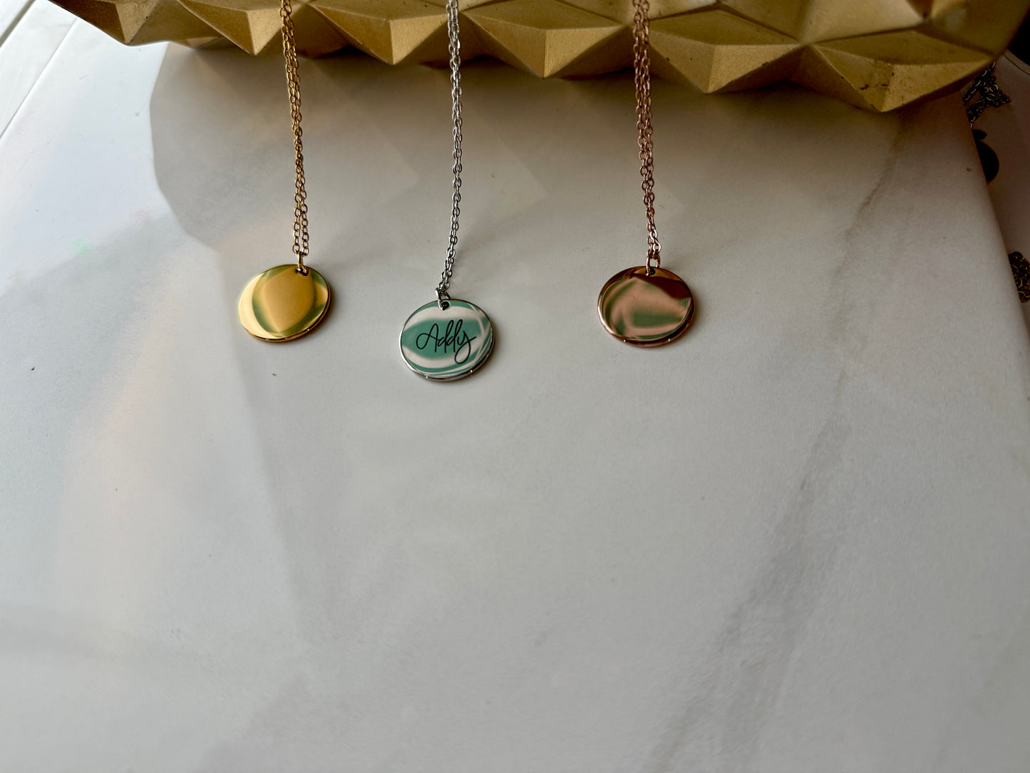 Three necklaces with round pendants on a white surface