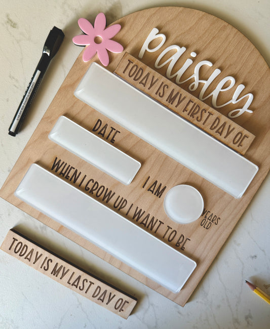 Wooden back to school board with engraved text and white dry erase boards on a light background