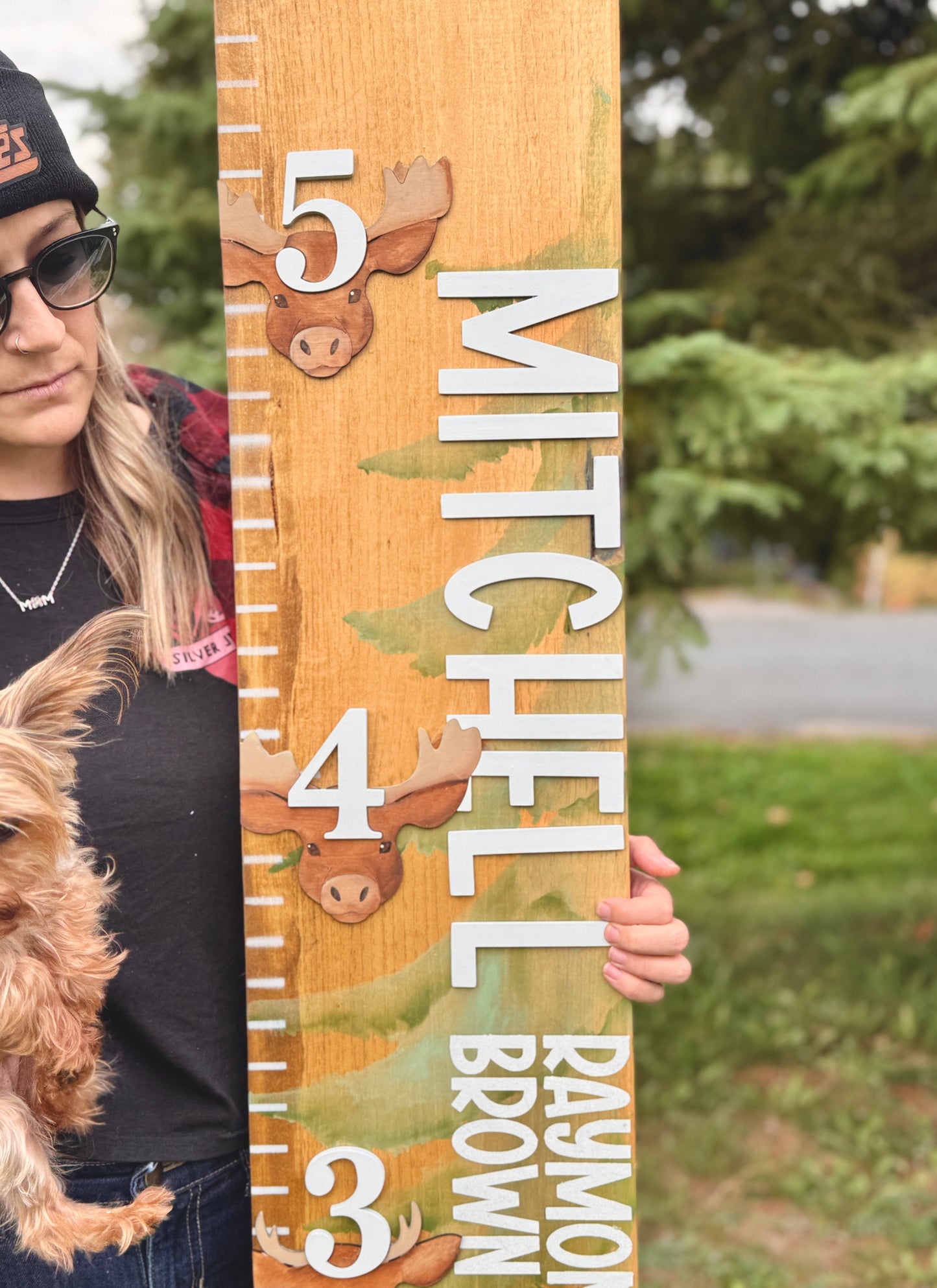 Person holding a wooden growth chart with animal illustrations and text.